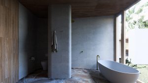 Bathroom with timer door and stone walls and floor with floor-to-ceiling window next to bath — sustainable new home — Eltham — Moloney Architects